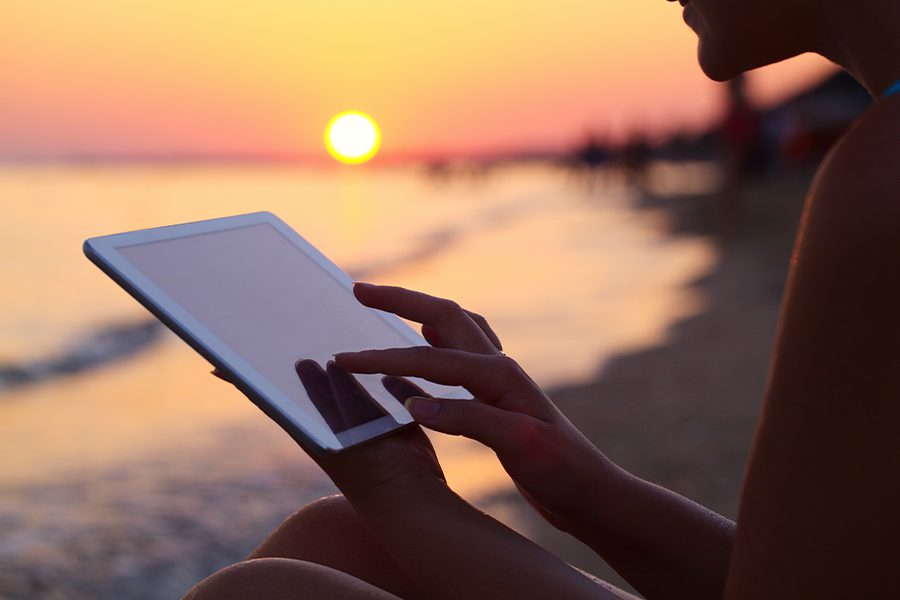 Client Center - Woman Using iPad Outdoors on the Beach at Sunset